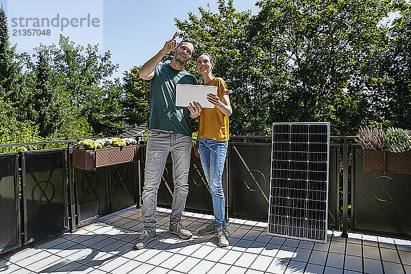 Man and woman discussing near solar panel in balcony