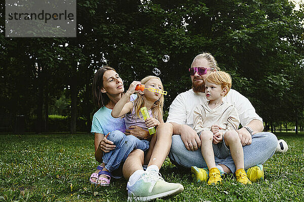 Parents with son and daughter sitting and enjoying in park