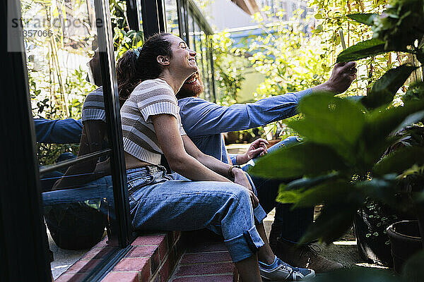 Happy multiracial couple taking selfie outside greenhouse