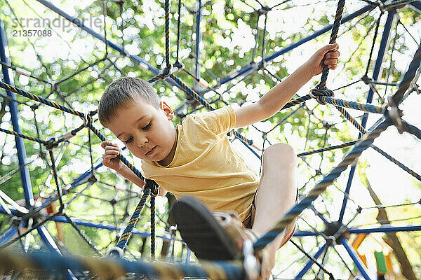 Boy playing on jungle gym rope in public park