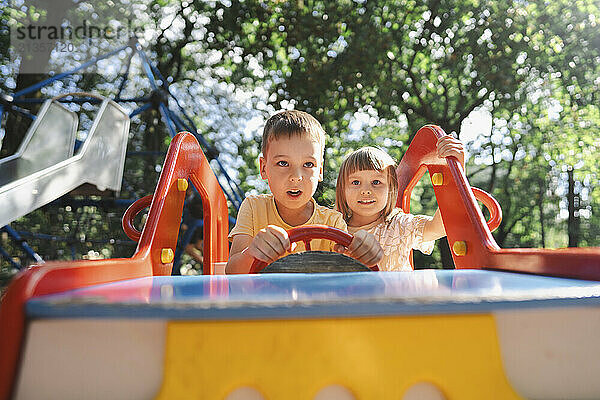 Boy and girl playing in toy car at public park