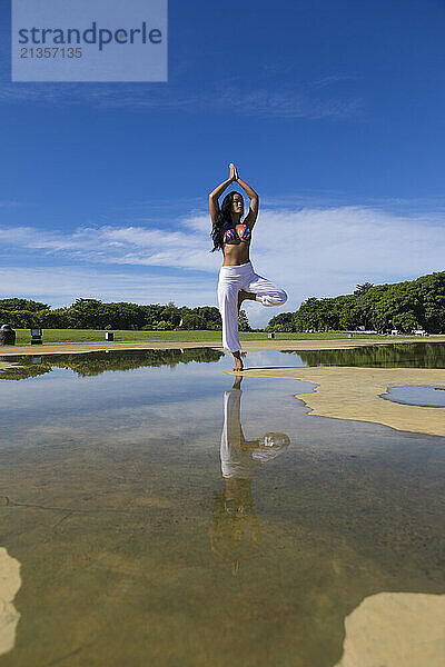 Yoga instructor doing tree pose in Bali at public park