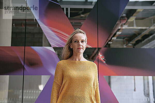 Confident mature woman standing in front of glass wall