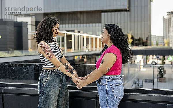 Young lesbian couple holding hands and standing on bridge