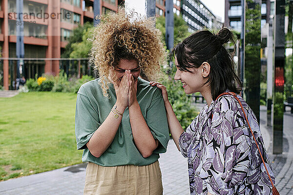 Cheerful lesbian couple laughing in front of building