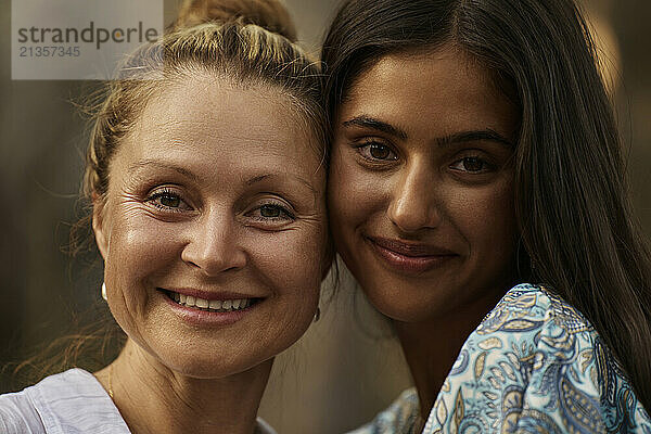 Smiling teenage girl cheek to cheek with mother