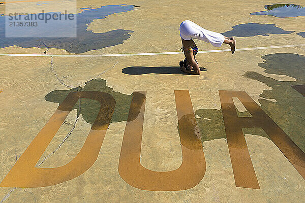 Flexible woman doing headstand on ground at public park