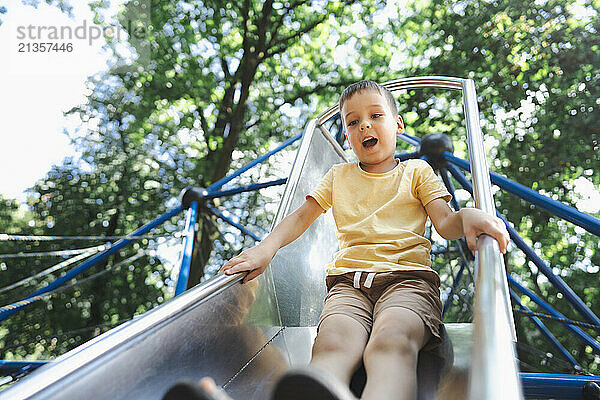 Boy sliding down on slide at playground