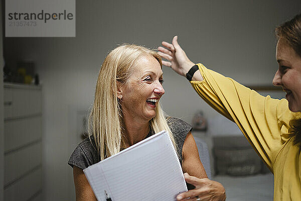 Happy blond woman holding paper spending leisure time with friend