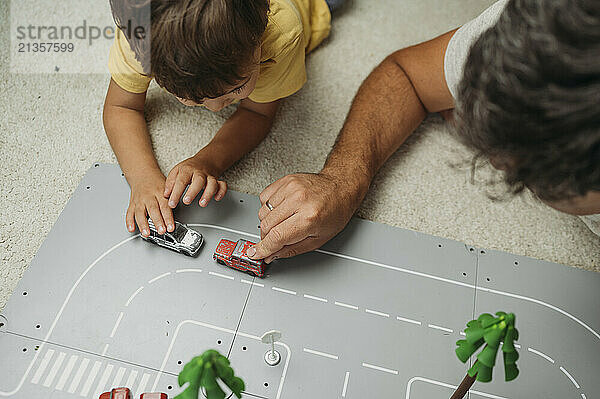 Father and son spending leisure time playing with toy cars at home