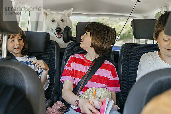 Siblings travelling in car with White Swiss Shepherd dog