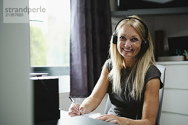 Smiling businesswoman wearing headset and working at home office