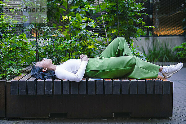 Woman relaxing and lying down on bench in park