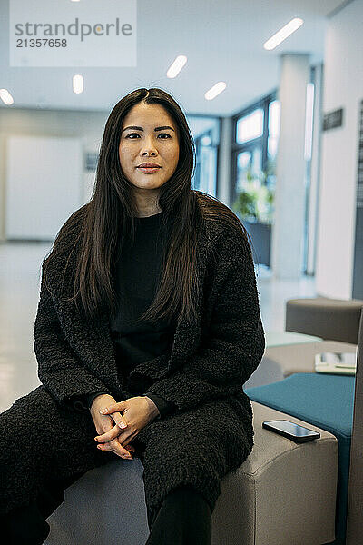 Beautiful businesswoman sitting with hands clasped at office