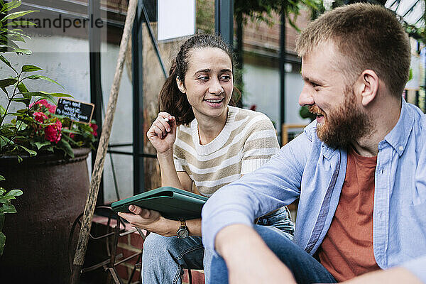 Young woman holding tablet PC talking with boyfriend