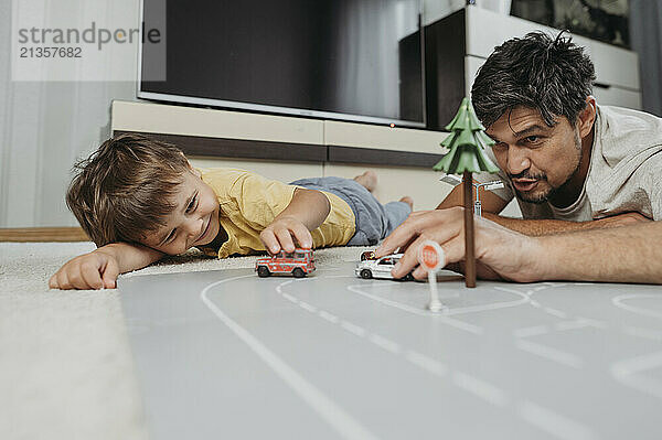 Father and son playing with toy cars at home