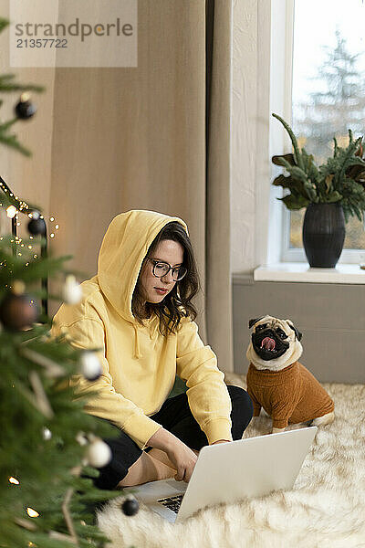 Young freelancer working on laptop near dog at home