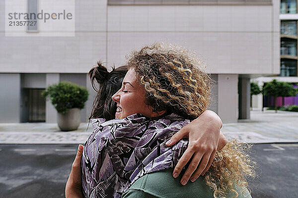 Happy lesbian couple hugging each other in front of building