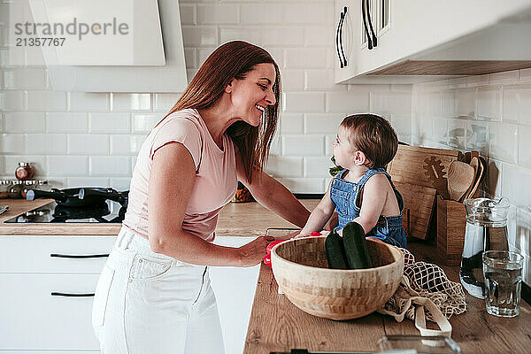 Happy mother enjoying with daughter sitting on kitchen counter at home