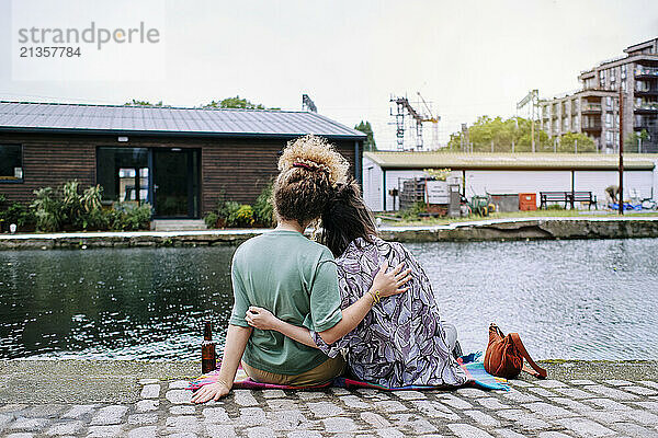 Loving young lesbian couple sitting at riverbank