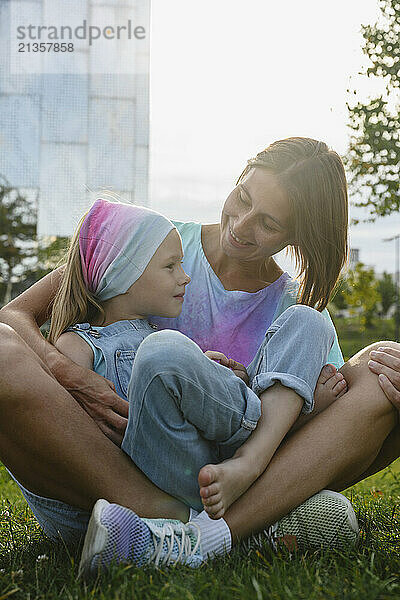 Mother and daughter sitting in park