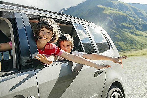 Happy brother and sister travelling in car near mountain