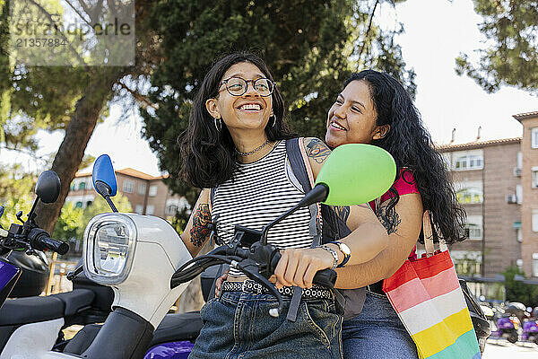 Happy lesbian couple sitting on motor scooter