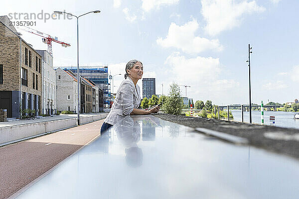 Contemplative woman leaning on surrounding wall at street