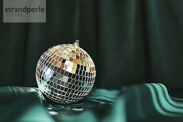 Shiny disco ball on green cloth