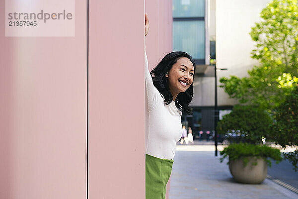 Happy woman spending leisure time near pink wall