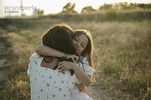 Happy girl hugging mother on field