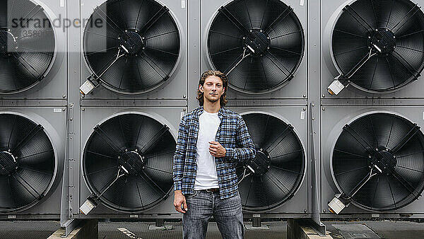 Confident young man standing in front of heat pumps