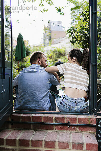 Couple talking and sitting at doorway of greenhouse