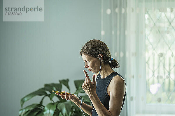 Mature woman using phone and listening music at home