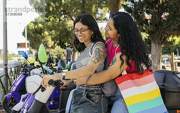 Happy gay couple sitting on motor scooter