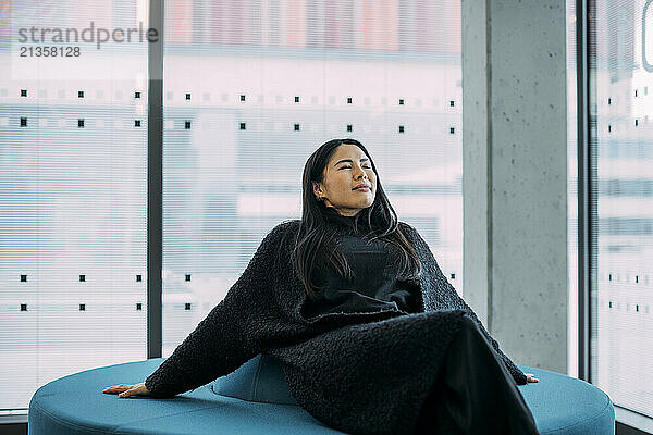 Businesswoman with eyes closed relaxing on seat in office