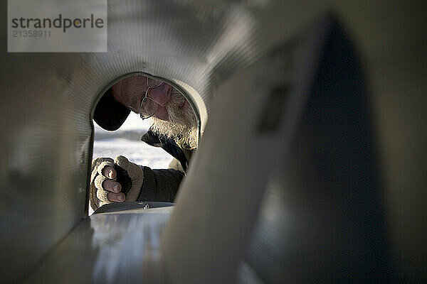 Bearded man looks inside mailbox for single letter.