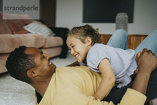 Happy father and daughter enjoying leisure time while lying down at home