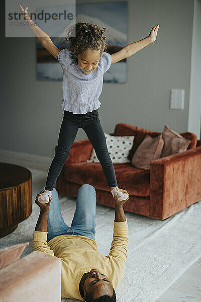 High angle view of daughter playing with father lying on carpet at home