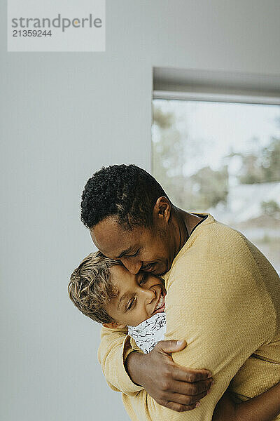 Affectionate father embracing son at home