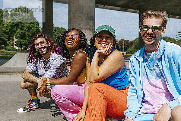 Portrait of happy male and female fashionable multiracial group of friends posing near overpass at sunny day