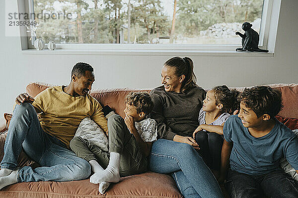 Happy multiracial family enjoying while sitting on sofa at home