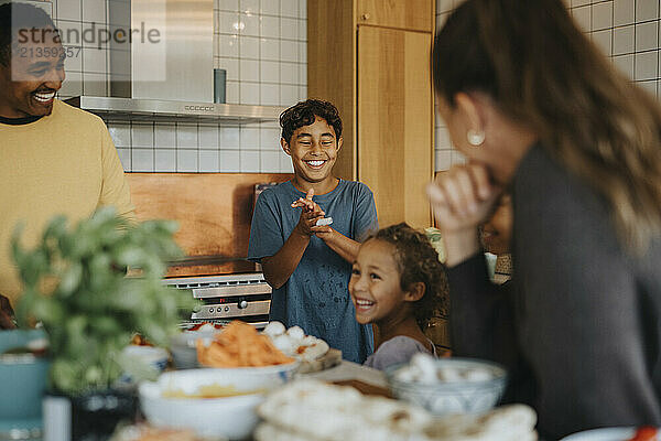 Happy boy applauding sister helping family in preparing food at home