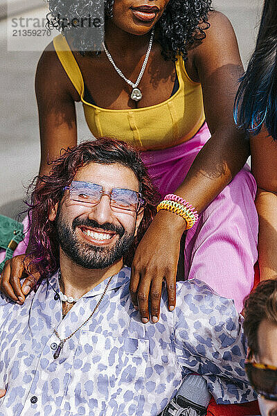 High angle view portrait of smiling man wearing sunglasses leaning on female friend at sunny day