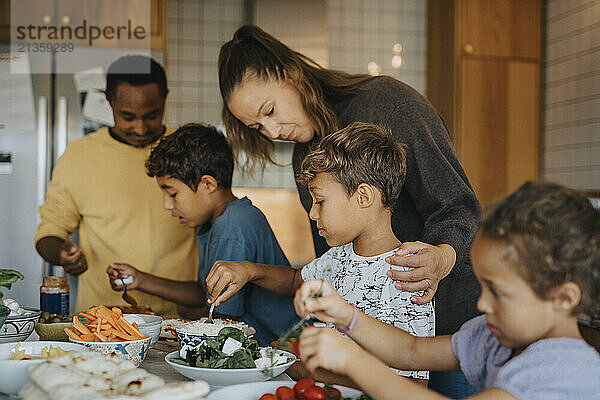 Parents teaching children to cook food in kitchen at home