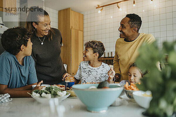 Happy multiracial family making pizza in kitchen at home