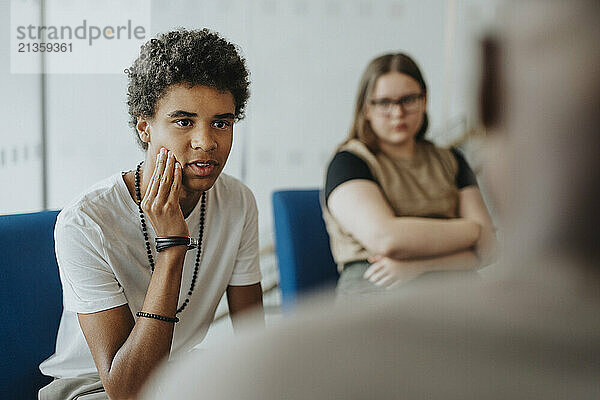 Teenage boy discussing with male counselor at high school