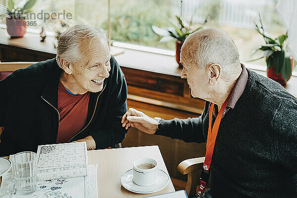 High angle view of senior men discussing while sitting at table in retirement home