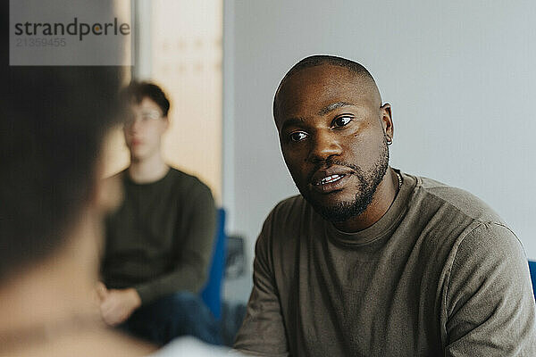 Male school counselor discussing with student at high school