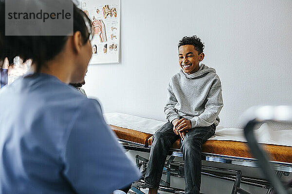 Happy boy sitting on examination table during visit in doctor's office